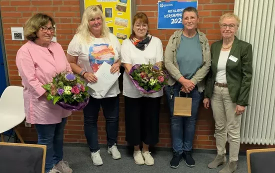 Fünf Frauen stehen vor einer Backsteinwand. Drei von ihnen haben ein Geschenk in der Hand.