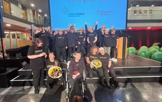 Die Trommelgruppe Unikat ist auf einer Bühne im Hintergrund ist eine Leinwand auf der