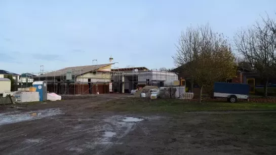 Richtfest beim Anbau der Kita Tausendschön Der Anbau ist von einem Gerüst umgeben. Auf dem Dach ist ein Richtkranz angebracht. Um den Bau herum stehen Baumaterialien.