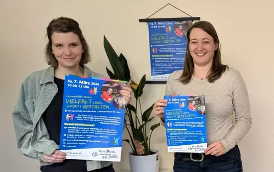 Zwei Frauen halten Werbeplakate der Lebenshilfe-Messe hoch.
